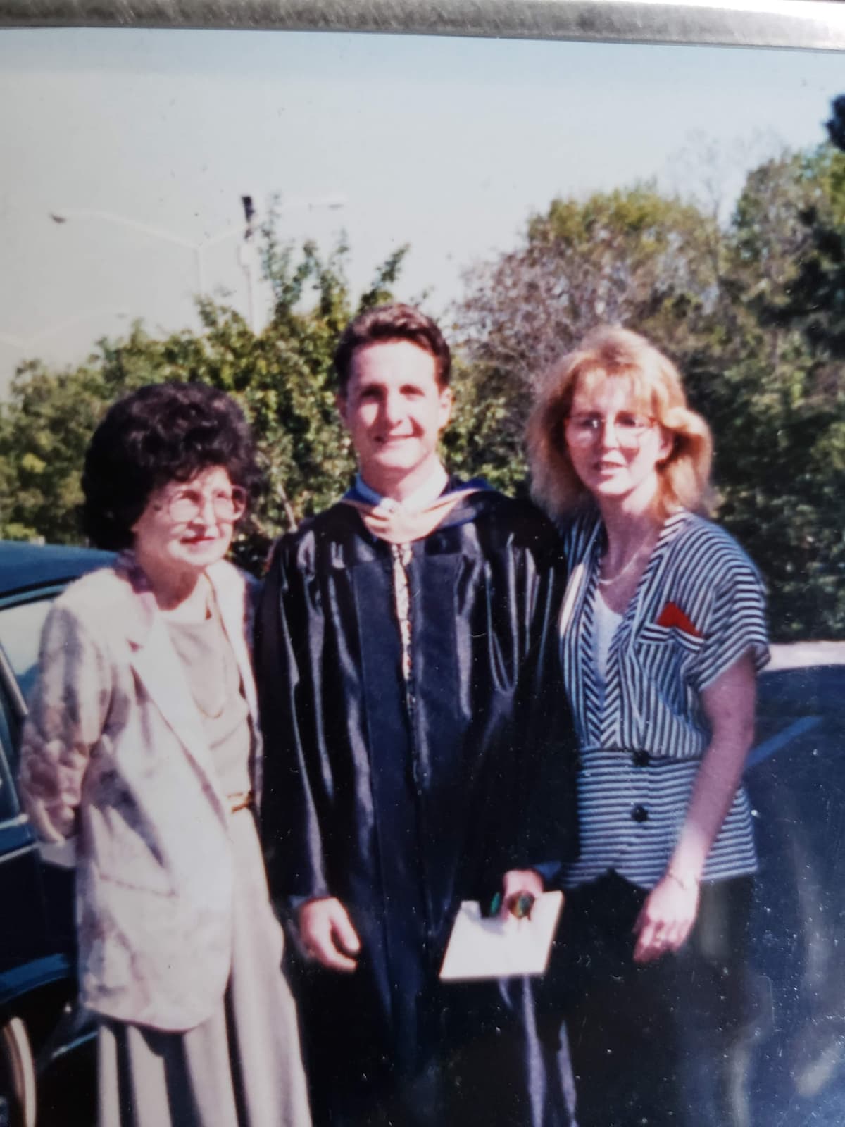 Chris at his graduation ceremony with his mother and grandmother